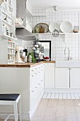 White, fitted kitchen cupboards on tiled wall