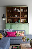 Grey sofa with scatter cushions in front of green dresser with shelving top section