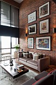 Gallery of artworks on brick wall of loft living room with retro furniture and glass wall