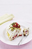 A slice of strawberry cake with meringue and pistachios