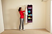 Woman holding dressing gown next to clothes rack and fabric shelving holding folded towels on wall