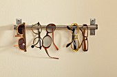Spectacles hung on stainless steel rod mounted on wall