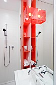 Waschbecken an Spiegelpaneel, seitlich orangerotes Regal mit Badutensilien und Duscharmatur im Duschbereich einer Singlewohnung
