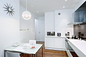 Esstisch mit Frühstrücksgedecken in offener, moderner Küche in Weiß