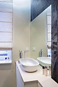 Waschbeckenschale auf Unterschrank vor eingelassenem Spiegel in Wand in moderner Badezimmerecke