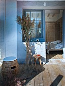 Rattan Hocker mit Sitzkissen und Pampasgras auf Holzterrasse mit Blick ins Schlafzimmer