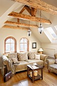 Traditional sofas in seating area below old wooden beams in attic