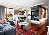 Edelholz-Parkettboden in offenem Wohnraum, Ledersofa und Beistelltisch auf Orientteppich in Loungebereich mit Fernseher