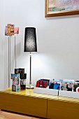 Collection of CDs, cube ornaments and table lamp on low sideboard