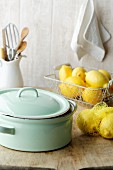 A cooking pot and fresh lemons on a wooden table