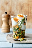 Soft-boiled eggs on a vegetable tartar in a glass