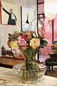 Bouquet with willow twigs in glass vase on vintage wooden surface