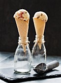 Two ice cream cones with strawberry sponge cake ice cream in glass bottles