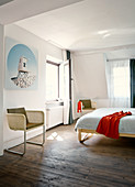 Freischwinger mit hellem Rattan Geflecht in schlichtem Schlafzimmer, rustikaler Dielenboden