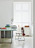 Modern desk and retro chair next to window with white roller blind