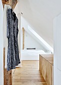 Dressing gown on coat hanger and cubby bed under sloping ceiling in converted modern attic room