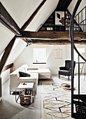 Sofa, Ohrensessel und Klassiker Beistelltisch, davor Teppich mit geometrischem Muster, Wendeltreppe zur offenen Galerieebene mit Bücherecke