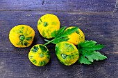 Pattypan squash with leaves on a wooden surface
