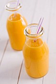 Orangensaft in zwei Flaschen mit Strohhalmen