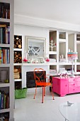 Delicate, orange metal chair next to pink, half-height cabinet in modern interior