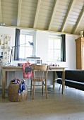 Sewing table; sewing machine on simple wooden table and basket of fabric remnants in rustic interior