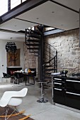 White classic rocking chair, kitchen counter, black metal spiral staircase and dining area below gallery against stone wall