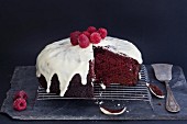 A Red Velvet cake with icing sugar and raspberries on a wire rack (sliced)