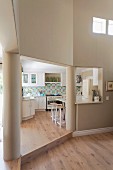 Doorway leading into kitchen flanked by columns; white fitted kitchen with mosaic splashback, retro cooker, retro fridge and breakfast bar