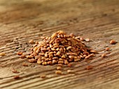 A pile of fenugreek seeds on a wooden surface