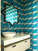 Moderner Waschtisch mit aufgesetzter Schüssel und sternenförmiger Spiegel, an gefliester Wand mit blau-weißem, dreidimensionalem Muster