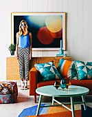 Blue patterned cushions with ethnic print on orange sofa and young woman in sunglasses in front of photo picture