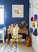 Junge sitzt im Kinderzimmer am Schreibtisch, an der Wand hängen Superheldenmasken