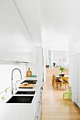 Open kitchen with white fitted wardrobes, view of dining table and chairs