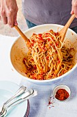 Vegane Spaghetti mit Soja-Gemüse-Sugo in einer Schüssel vermischen