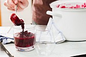 Red berry compote being transferred to dessert glasses