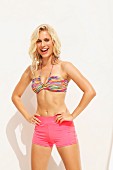 Blonde Frau in pinken Shorts und bunt gestreiftem Bikinioberteil