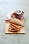 Various types of sausages and goose liver on a chopping board
