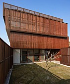 Karger Innenhof eines modernen, indischen Wohnhauses mit Sonnenschutz durch vorgesetzte Elemente aus schmalen Holzlatten