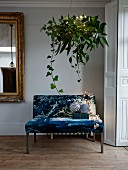 Hanging basket draped with leaves and ivy above Christmas decorations on elegant couch