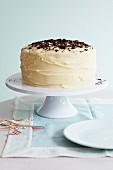 A large celebration cake with white buttercream icing topped with chocolate curls
