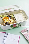 Yoghurt with dried apricots, bananas and plums in a lunch box