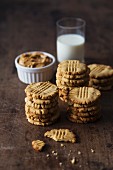 Peanut butter cookies with a glass of milk on a dark wooden surface