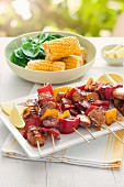 Pork skewers with peppers served with corn cobs