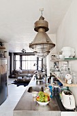 Küchenzeile mit Edelstahl Arbeitsplatte unter Pendelleuchten im Industriestil in offenem Wohnraum