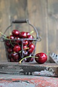Fresh cherries in a wire basket and in front of it