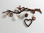 A stylised wooden twig hung with various Christmas tree decorations in natural colours