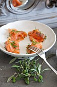Salmon with dill in white bowl next to olive sprig