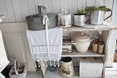 Kitchen utensils on vintage shelves and zinc container on lace runner