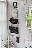 In Zimmerecke aufgehängter Topfdeckelhalter mit beschrifteten Tafeln, an weiss lasierter Holzwand