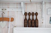 Old wooden skittles on narrow shelf against wooden wall stained white